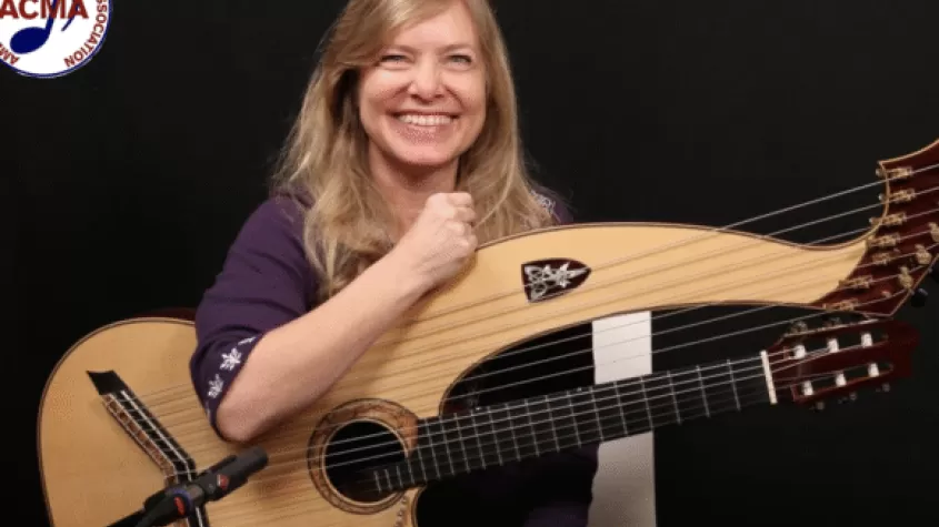 Muriel Anderson holding a harp guitar; ACMA logo in corner