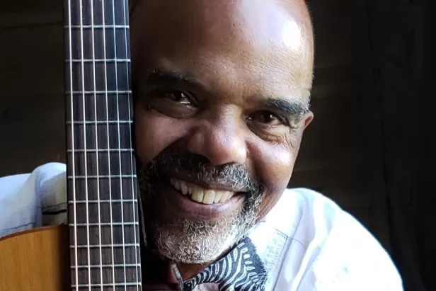 man hugging a guitar while smiling
