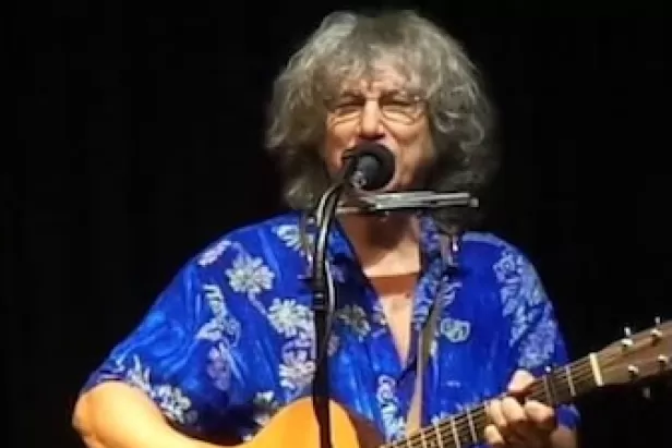 Image of Rod MacDonald playing guitar with a microphone
