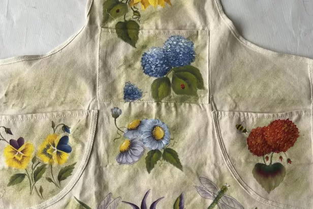 beige apron with different flowers painted on it.
